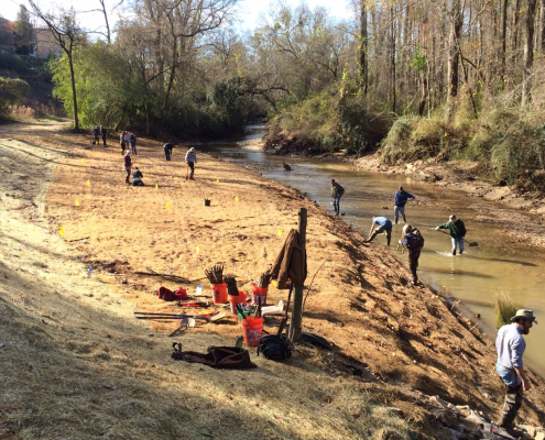 A group working along the banks and channel of a stream restoration site.